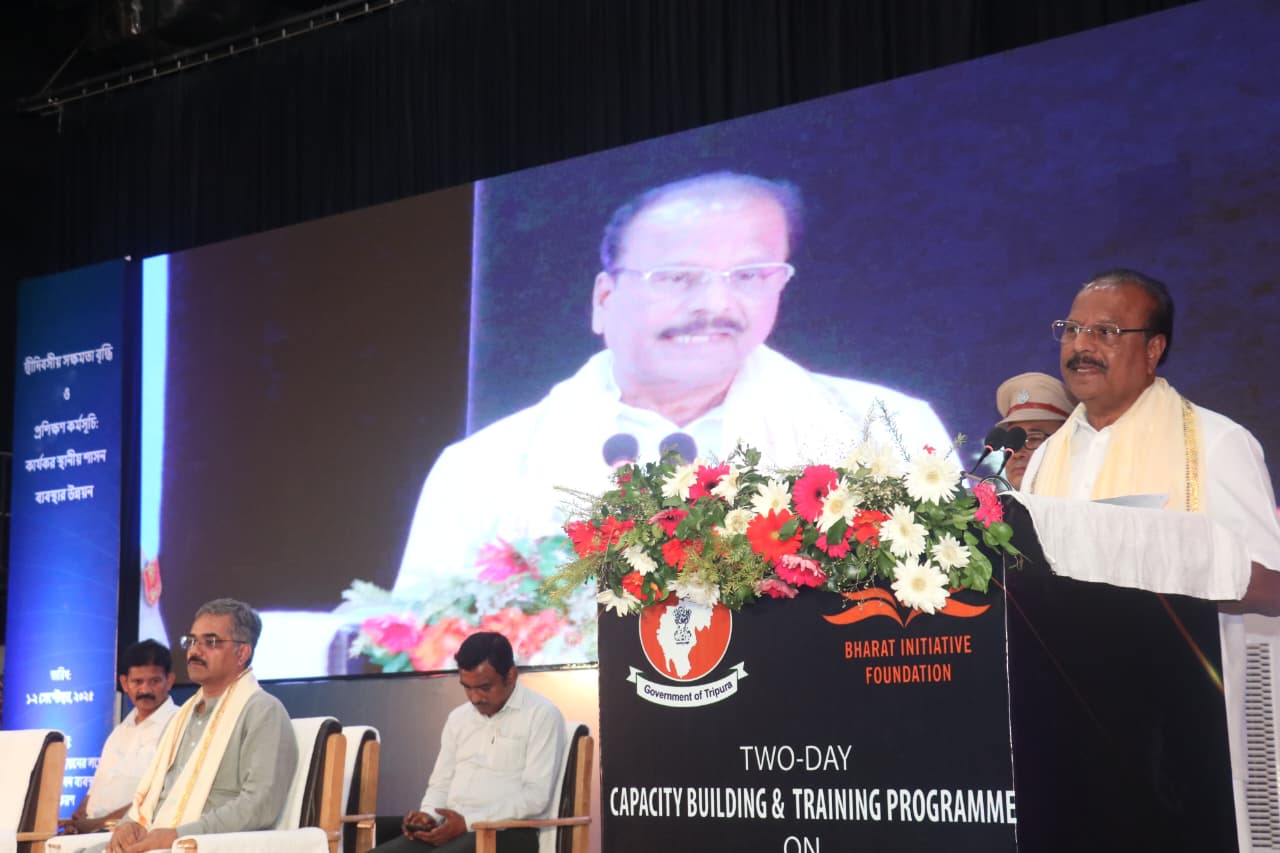A speaker at the podium during a session, with guests seated on stage