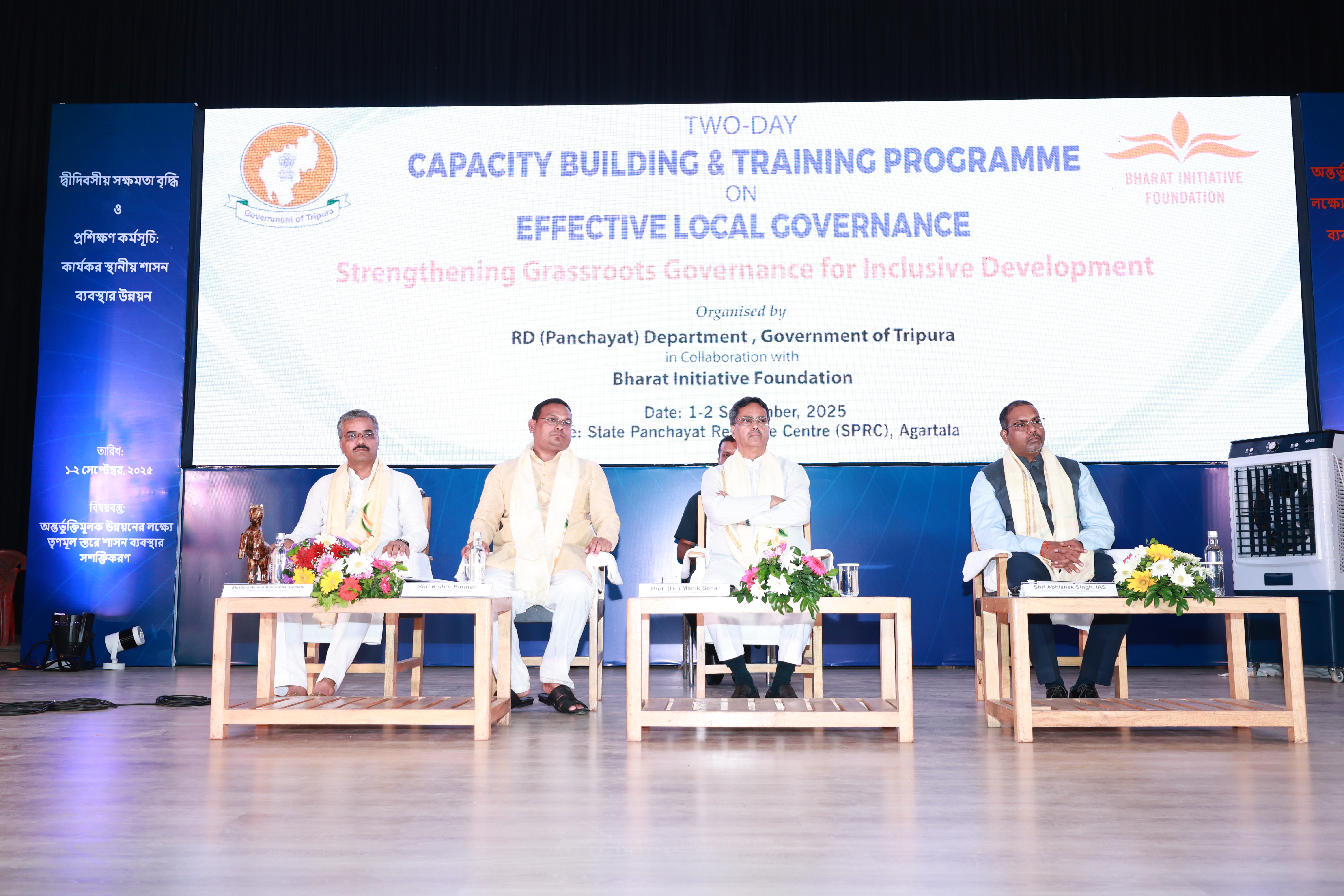Four guests seated at tables on stage beneath the capacity-building programme banner